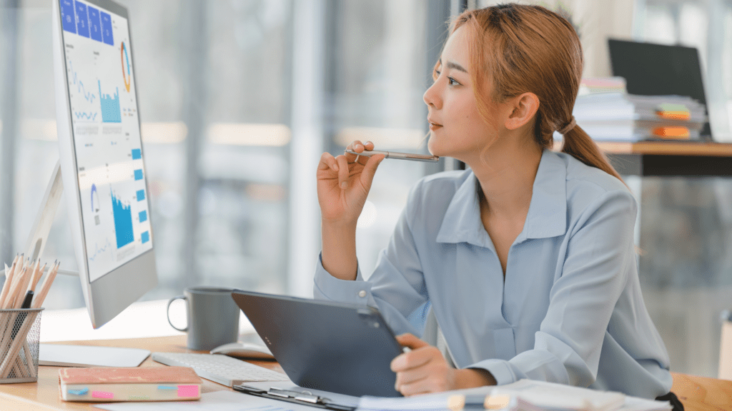 Woman sitting at a desk looking at a computer screen with trends.